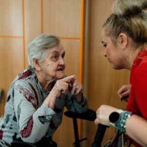 Elderly woman and caregiver in conversation inside a room in Karviná, Česko.